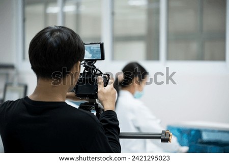 Videographer working with his camera.Professional media production recording at studio.Filming with professional camera concept. Royalty-Free Stock Photo #2421295023
