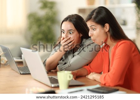 Shocked tele workers checking laptop working at home Royalty-Free Stock Photo #2421295185