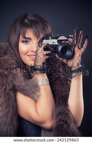portrait of beautiful young retro woman holding vintage camera