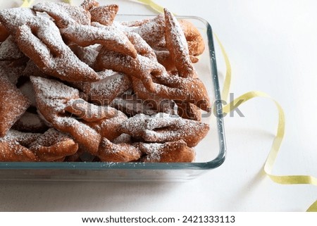 Carnival sweets. Homemade bugnes from Lyon for the carnival sprinkled with icing sugar on white background. Overhead view. Carnival season. Copy space.