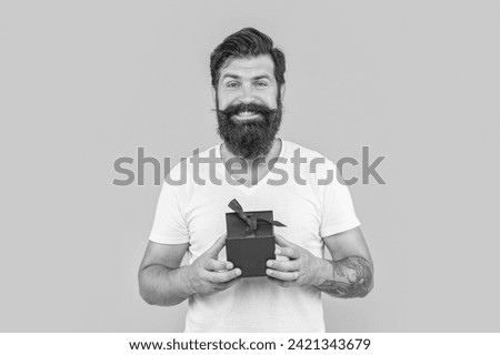 happy bearded man hold present box in studio. bearded man hold present box on background.