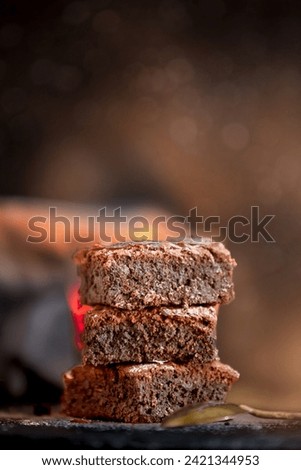 Homemade dark chocolate fudge brownies cake stacked on stone plate with copy space, dark background