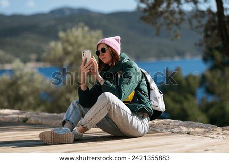 Girl hiker taking photos on smartphone.