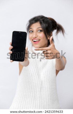 Portrait of a smiling young woman pointing finger on blank smartphone screen isolated on a white background, Selective focus. A little bit of depth of field
