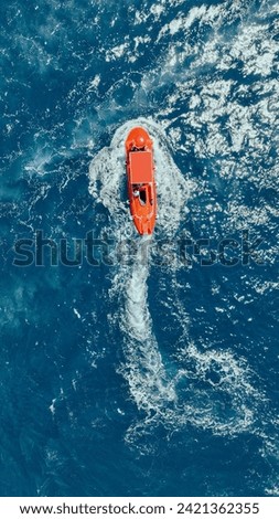 Red Lifeboat Speeding Through Blue Ocean Waters Royalty-Free Stock Photo #2421362355
