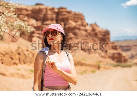 girl in the canyon traveling through the canyon with a phone and a backpack in the summer at sunset