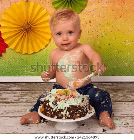 Colorful images shot during the first birthday party of a little blonde boy smashing his birthday cake with wooden spoons Royalty-Free Stock Photo #2421364893
