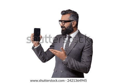 Young Pakistani business man in suit, wearing eyeglasses, holding blank screen smartphone and pointing to it, copy space for advertising, isolated on white background Royalty-Free Stock Photo #2421364945
