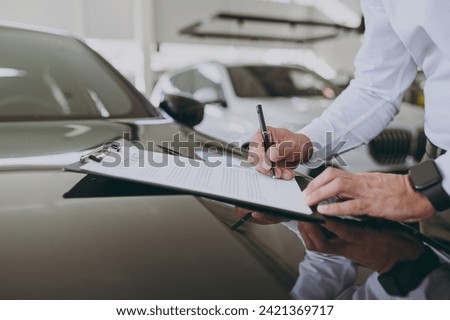 Cropped close up photo man customer male buyer client signs contract documents on hood choose auto want to buy new automobile in car showroom vehicle salon dealership store motor show. Sales concept
