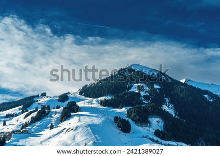 A serene snowy landscape under a partly cloudy sky, ideal for concepts of tranquility and natural beauty. The pristine snow blankets the mountain, offering a peaceful escape