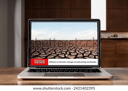 Laptop displaying climate change news on wood table.