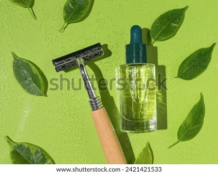 A razor and a bottle of oil on a green background with leaves. Skin care after shaving.