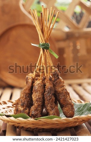 Chicken satay on a woven bamboo plate covered with banana leaves Royalty-Free Stock Photo #2421427023