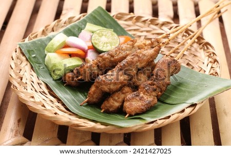 Chicken satay on a woven bamboo plate covered with banana leaves Royalty-Free Stock Photo #2421427025