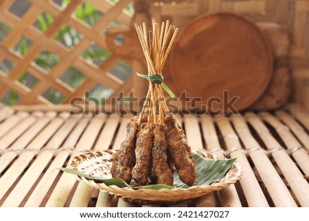 Chicken satay on a woven bamboo plate covered with banana leaves Royalty-Free Stock Photo #2421427027