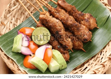 Chicken satay on a woven bamboo plate covered with banana leaves Royalty-Free Stock Photo #2421427029