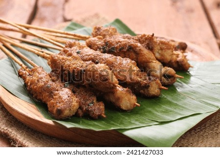 Chicken satay on a woven bamboo plate covered with banana leaves Royalty-Free Stock Photo #2421427033