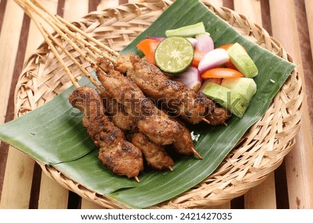 Chicken satay on a woven bamboo plate covered with banana leaves Royalty-Free Stock Photo #2421427035