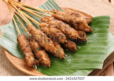 Chicken satay on a woven bamboo plate covered with banana leaves Royalty-Free Stock Photo #2421427037