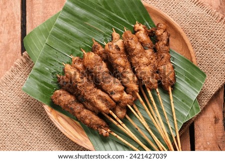 Chicken satay on a woven bamboo plate covered with banana leaves Royalty-Free Stock Photo #2421427039