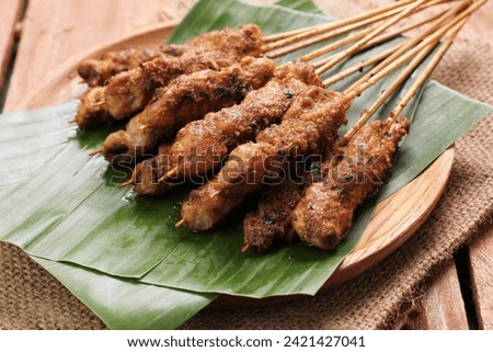 Chicken satay on a woven bamboo plate covered with banana leaves Royalty-Free Stock Photo #2421427041