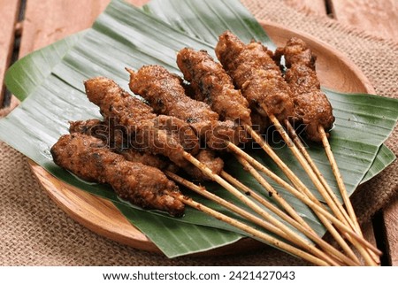Chicken satay on a woven bamboo plate covered with banana leaves Royalty-Free Stock Photo #2421427043