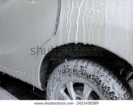 A picture of a white car that is being washed using car cleaning foam