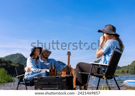 happy family daughter takes pictures for mom and dad  at the campground by the riverside, mountain and blue sky background,