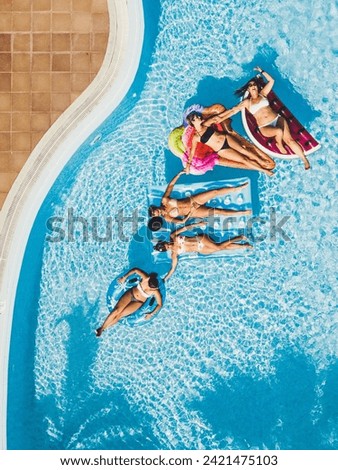Friends caucasian people women have fun at the pool - concept of friends enjoying summer holiday vacation in hotel travel resort - bikini girls with coloured lilos together