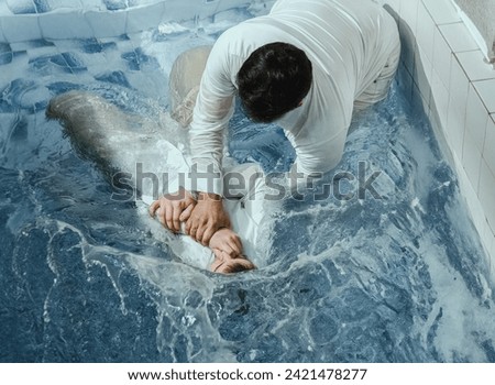 A Protestant pastor baptizes a man in water in the name of Jesus Christ Royalty-Free Stock Photo #2421478277