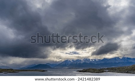 A picturesque mountain range of the Andes against a cloudy sky. In the foreground is the Beagle Channel with rocky islets. Argentina. Patagonia. Tierra del Fuego Archipelago