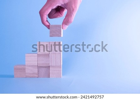 A left-aligned photo of building blocks stacked in a stair-like manner. Images of stock prices, growth, stairs, future, future, and upbringing.
