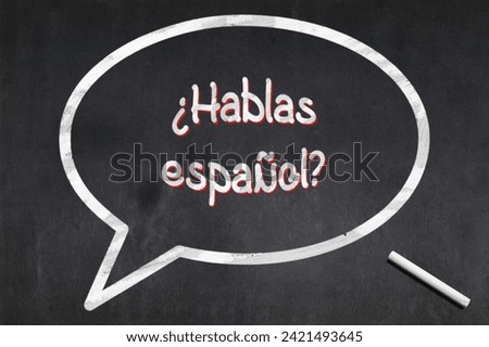Blackboard with a bubble drawn in the middle with the short phrase in Spanish "¿Hablas español?", meaning "Do you speak Spanish?".