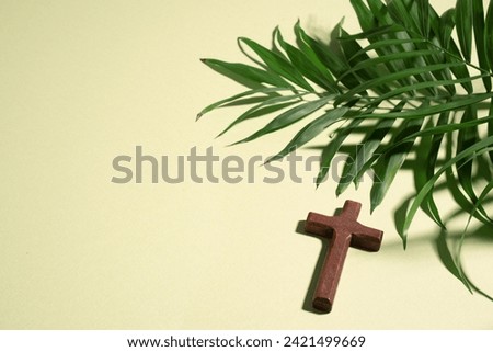 Palm Sunday. Wooden christian cross and palm leaves on green pastel background, top view, copy space. Palm sunday festival concept. Royalty-Free Stock Photo #2421499669