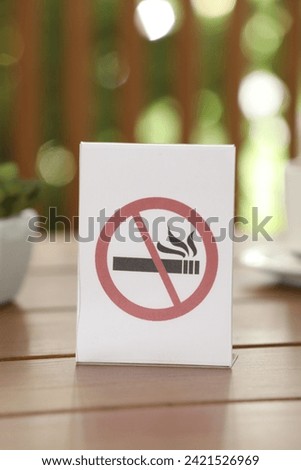 No Smoking sign on wooden table outdoors, closeup