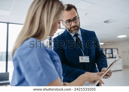 Pharmaceutical sales representative talking with doctor, presenting new medication. Nurse talking with hospital director, manager about contract, documentation. Medical, healthcare unions. Royalty-Free Stock Photo #2421531035