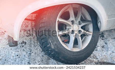 The wheel of the car bent, sparked violently, the consequences of hitting a pothole on a winter road. The car's wheel twisted from a strong impact, The front wheel of the car broke.