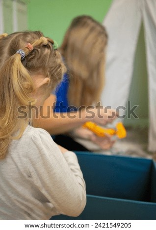 a child in kindergarten takes toys out of a drawer. teacher in the background