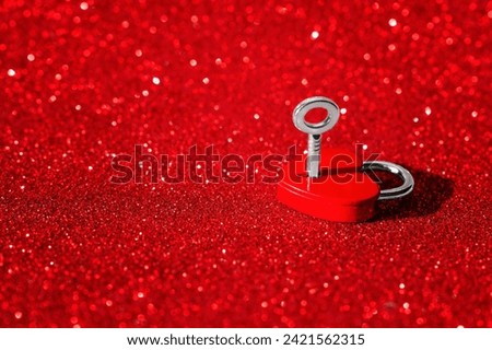Red heart-shaped padlock with key isolated on a sparkling red background with copy space. Romance and love related concept.