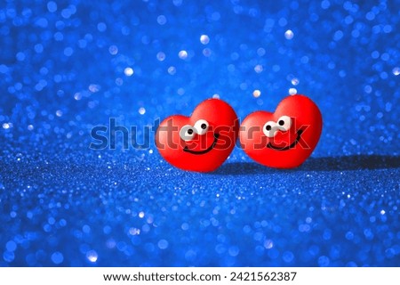 Two smiling anthropomorphic heart characters set on a glittering blue background. Valentine's Day card radiating love and happiness.