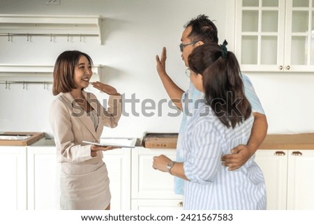 Real estate woman agent holding tablet and life insurance to couple for signature and consultant talk in a house for sale.Young couple signing contract.business and real estate concept