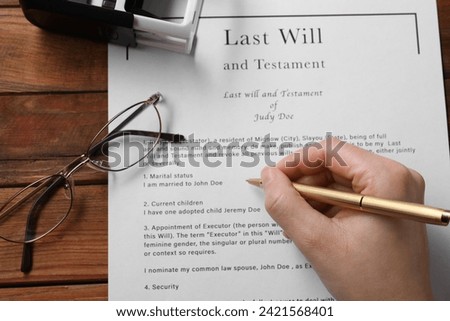 Woman signing Last Will and Testament at wooden table, above view Royalty-Free Stock Photo #2421568401