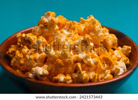 Caramel Popcorn in wooden bowl isolated on blue background.