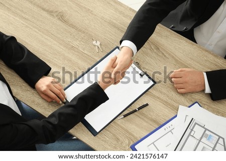 Real estate agent shaking hands with client at table in office, above view