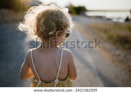 Rear view of blonde girl in summer outfit on walk during summer vacation, concept of beach holiday.