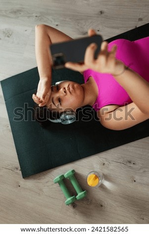 Woman resting after home workout, New Year's resolutions, healthy lifestyle, losing weight and selfcare. Concept of morning or evening exercise. Royalty-Free Stock Photo #2421582565