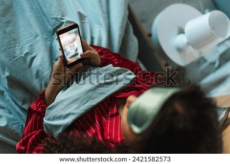 Woman setting alarm before going to sleep. Concept of sleep routine. Insomnia a sleep problems among adults. Royalty-Free Stock Photo #2421582573