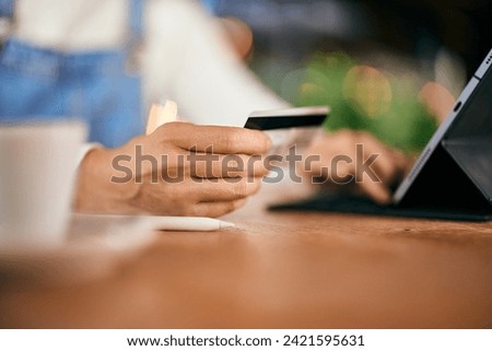 Close-up photo, female using a digital tablet, holding a credit card, entering data online.