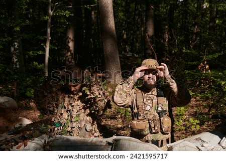  two elite soldiers meticulously prepare for a dangerous military operation, embodying strategic readiness, discipline, and teamwork as they gear up for a mission fraught with intensity and peril. Royalty-Free Stock Photo #2421595717