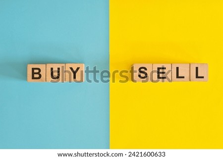 Buy versus sell in business and investing concept. Wooden blocks typography in bright blue and yellow background.